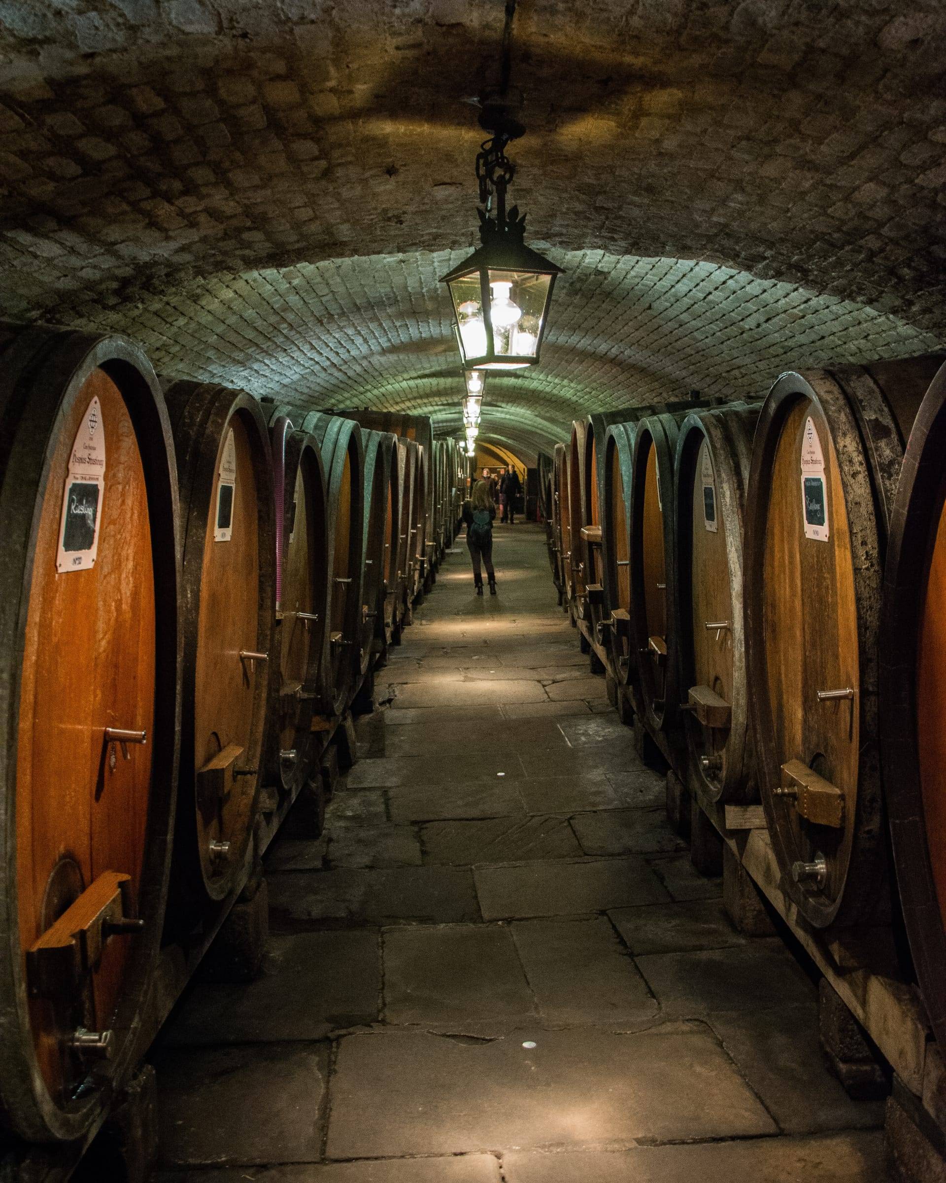 Bodega abovedada de ladrillo con grandes barricas de roble a los lados y un farol encendido