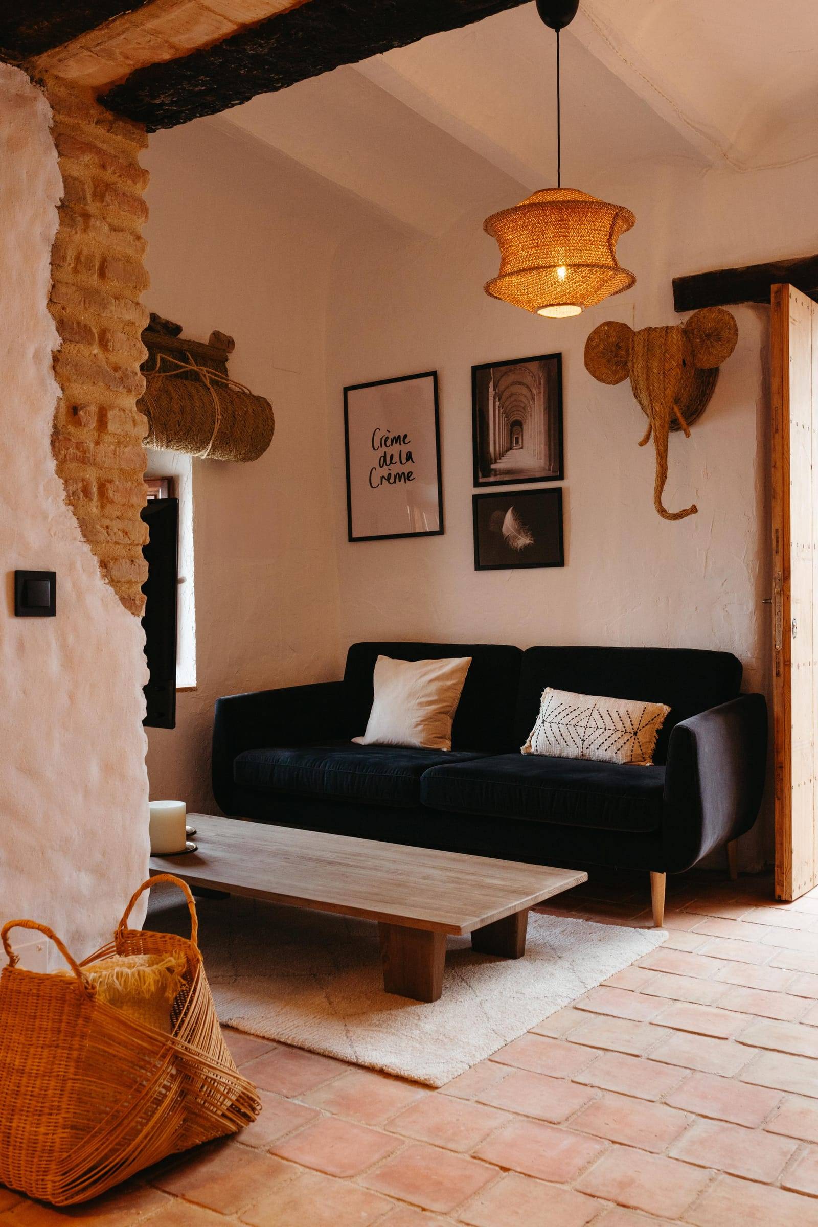 Rincón de salón con sofá negro, mesa baja de madera y cuadros en blanco y negro